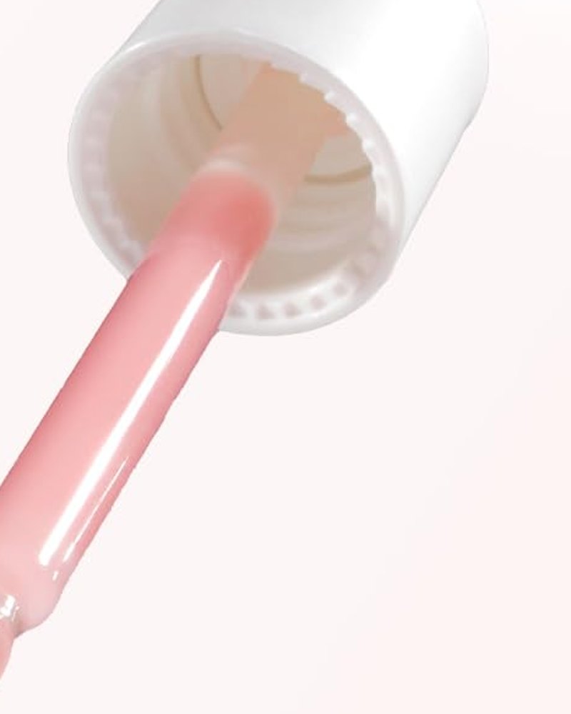 白いキャップの下、ガラススポイトの中のメディキューブのピンク色の美容液のクローズアップ