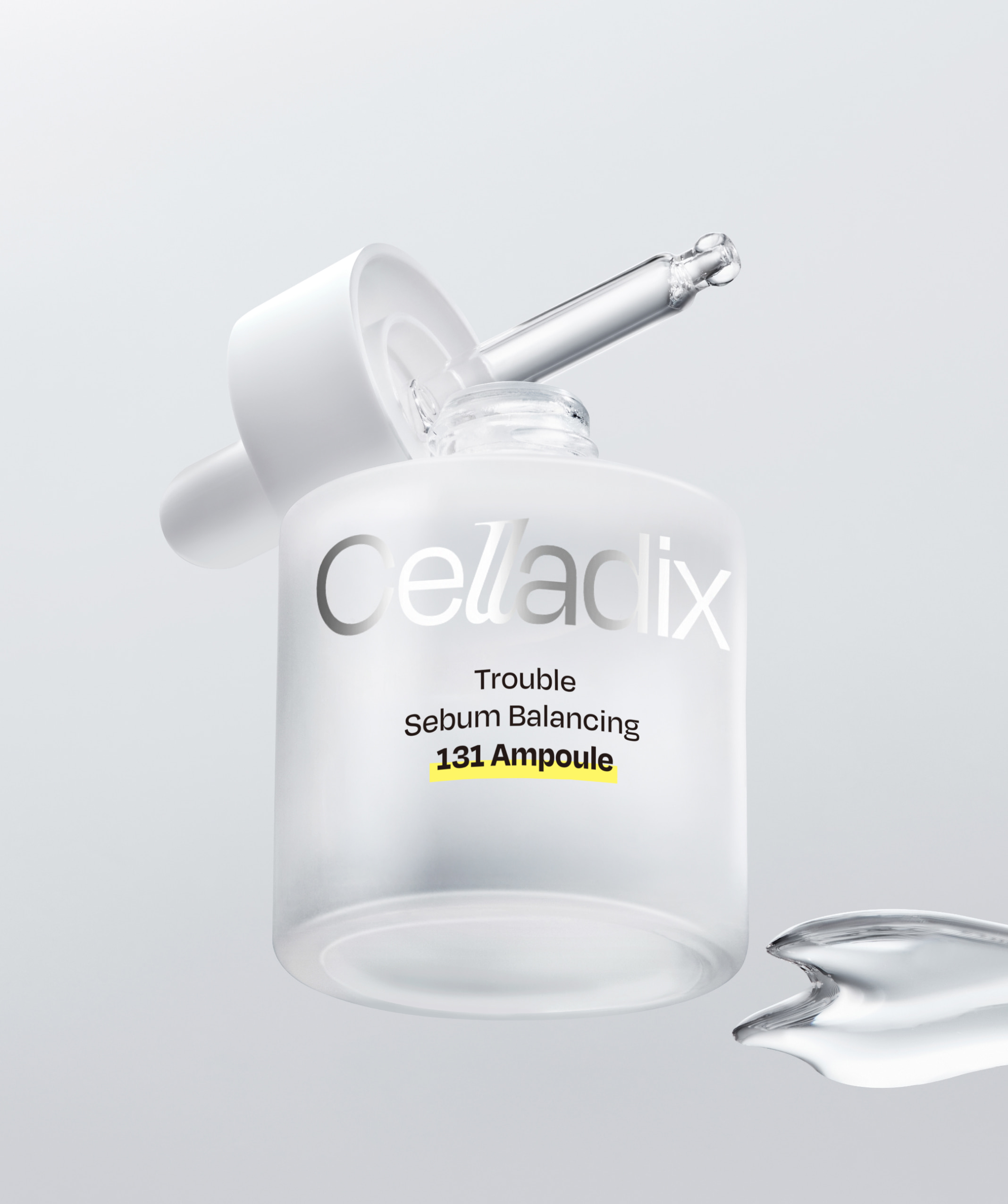 傾斜漂浮的 Celladix「Trouble Sebum Balancing 131 Ampoule」瓶，滴管蓋被掀起，旁邊有一灘透明有光澤的液體。