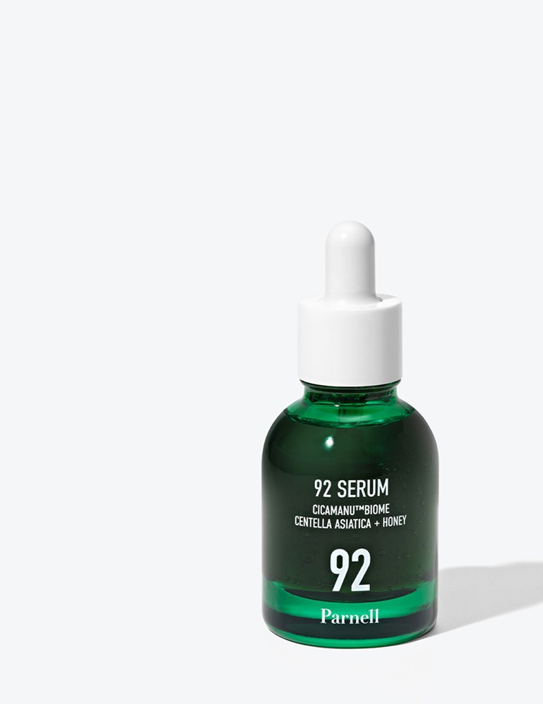 淺灰色背景上，附白色滴管的半透明深綠色瓶，標籤為「92 SERUM CICAMANU™BIOME CENTELLA ASIATICA + HONEY 92 Parnell」。