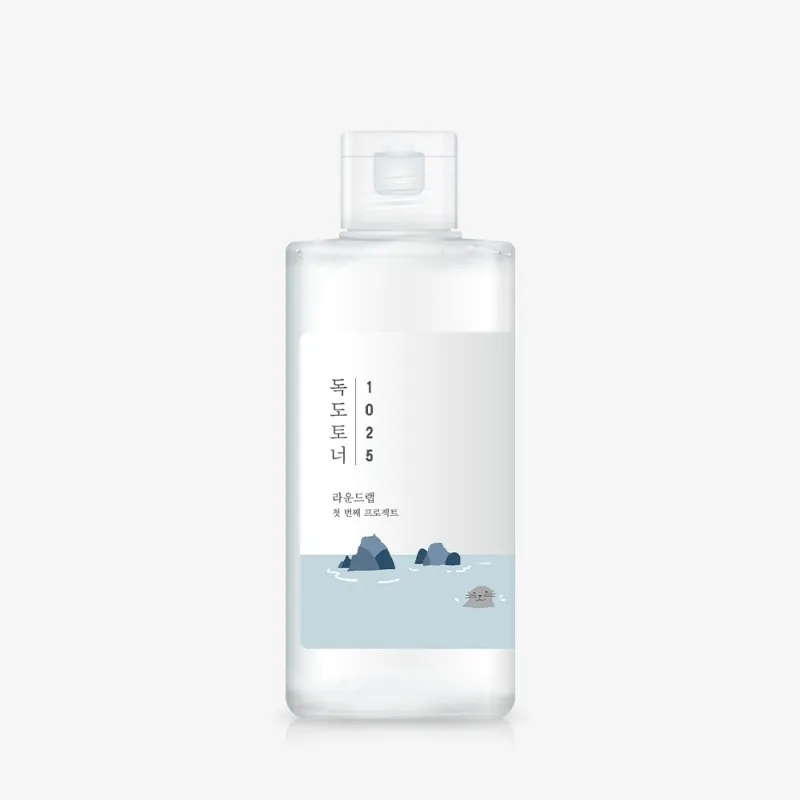 薄いグレーの背景に、すりガラス調のフリップキャップ付きの透明なプラスチックボトル。白いラベルに縦書きで「독도토너 1025」とあり、岩の小島とアザラシの小さなイラストが描かれている。
